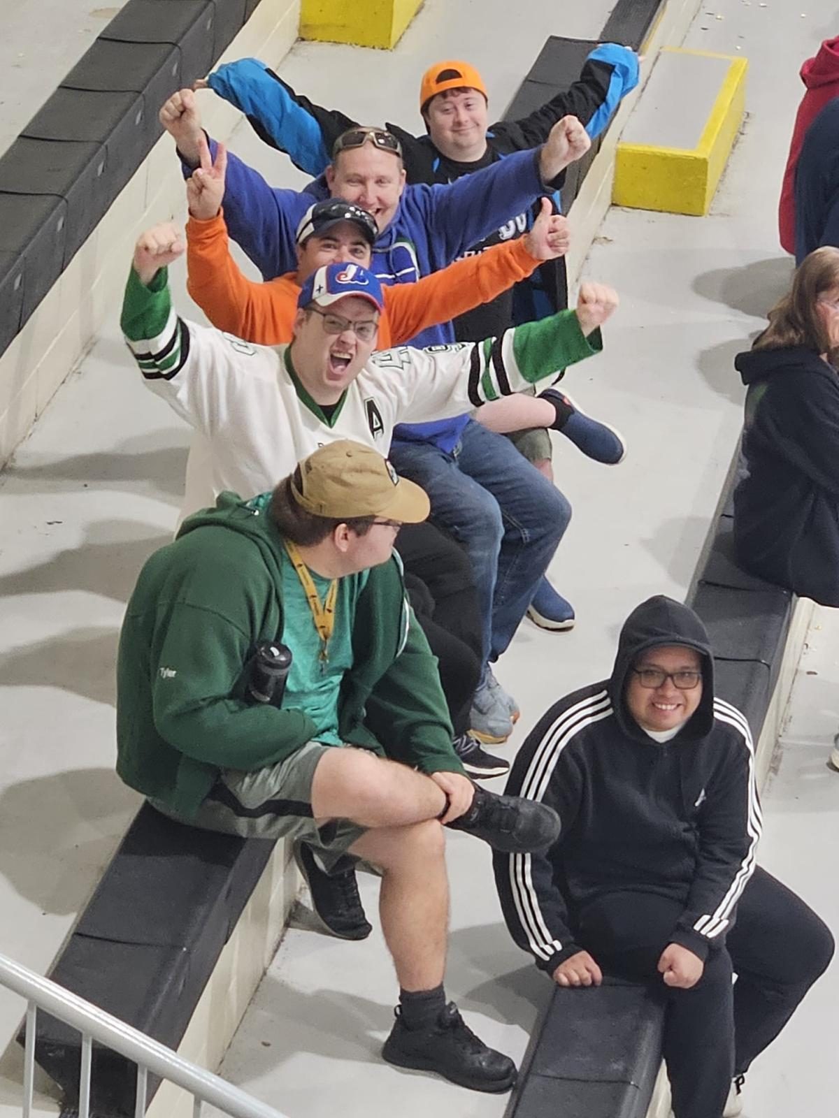 Participants cheering with their arms raised in the stands at a hockey game