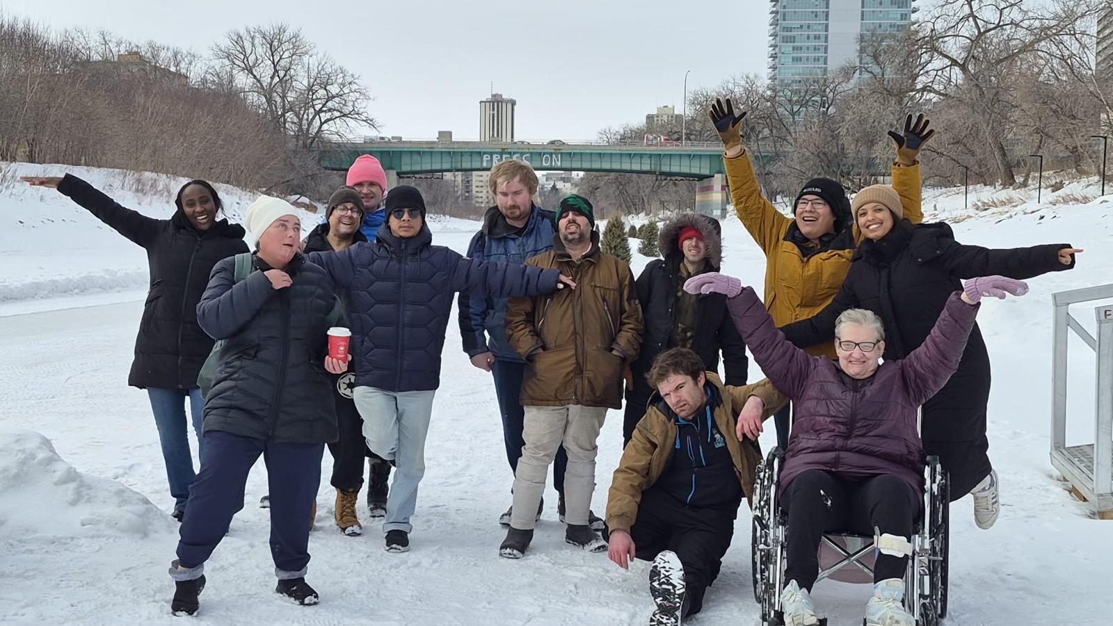 Twelve Day Program participants and staff posing with arms outstretched on the snow-covered river trail in winter
