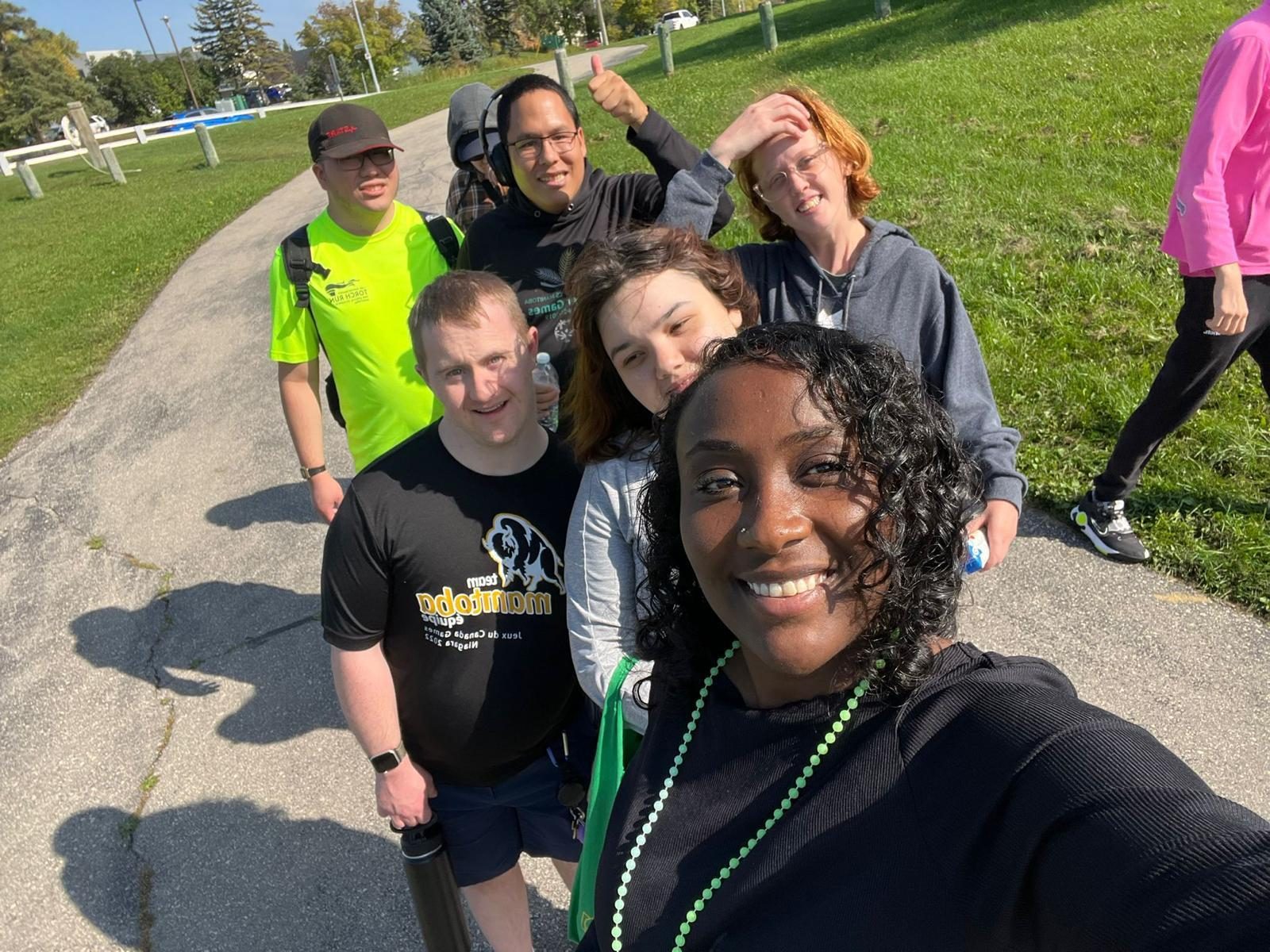 A group of participants and a support worker walking together along a path on a sunny day
